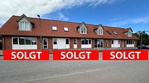 Den lave bygning på Centervejen i Græsted set fra vejen. Tre solgt-bannere er lagt oven på fotoet, ét for hver af de tre ejerlejligheder.