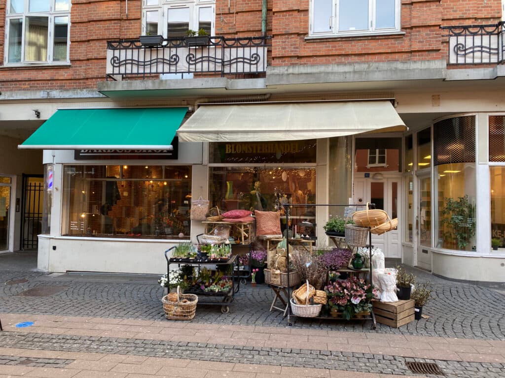 Slotsgade i Hillerød med de to udlejede erhvervslejemål i stueetagen og gående i gågaden foran.